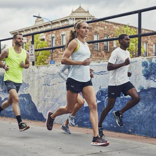 Four runners run by a mural in Flagstaff while high altitude training