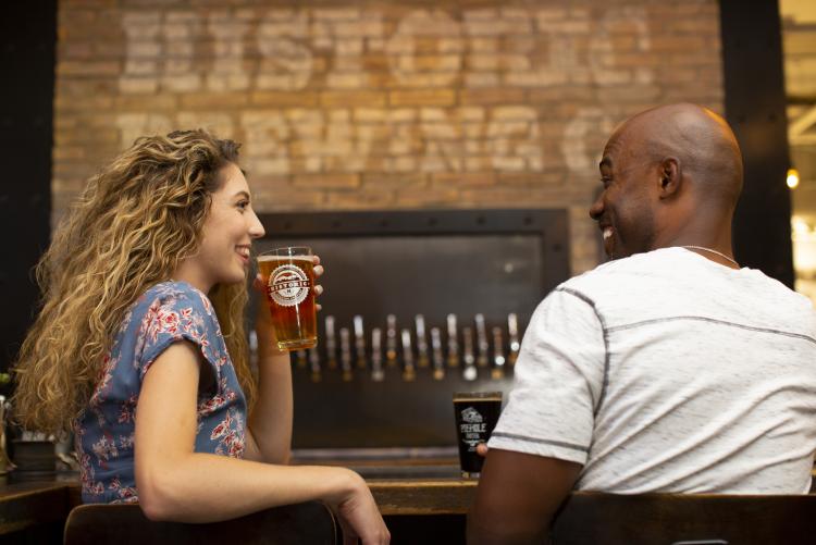 a man and woman enjoying pints of beer and good conversation at a Flagstaff, AZ brewery