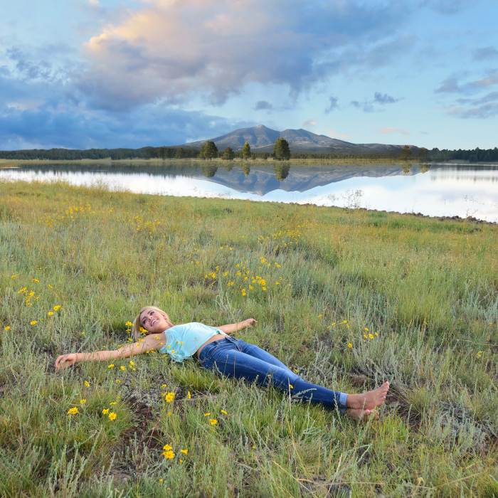 woman lying in the grass near a lake