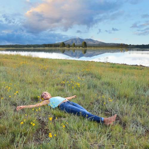 woman lying in the grass near a lake