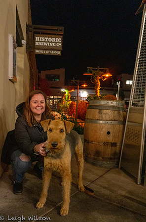 A woman positing in front of Historic Brewing with her dog.